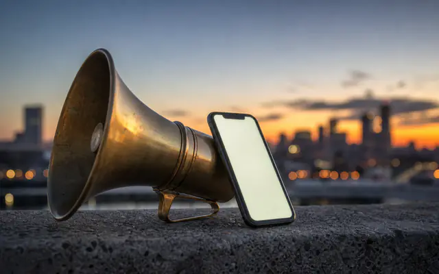 Brass megaphone on a concrete ledge with city dusk bokeh behind