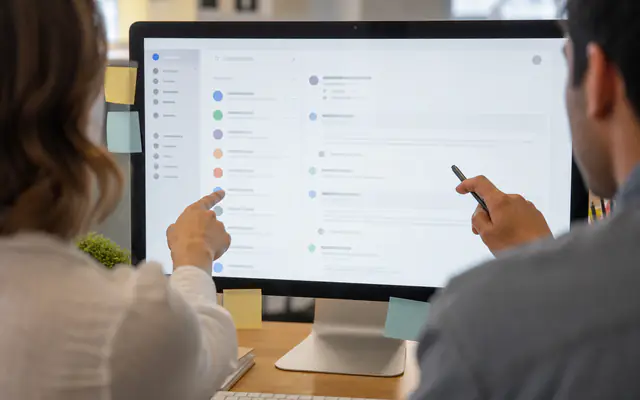 Two teammates pointing at a shared conversation monitor in an office
